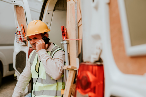 Le conducteur de la flotte au téléphone pour un contrôle à l'arrière de la camionnette garée.